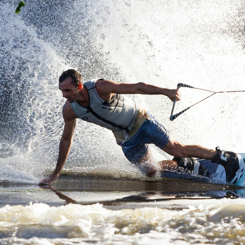 Man tilting and touching the water while riding a wakeboard