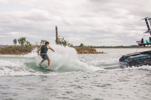 Man wakesurfing behind a boat on a Phase 5 wakesurf board – wakesurf gear collection from Wakesports