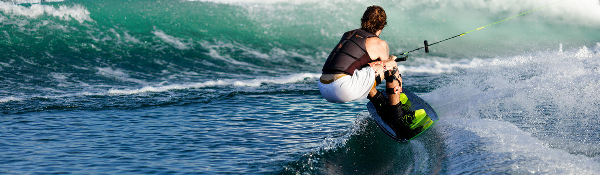 A wakesurfer cutting into the wake for a huge wake to wake jump.