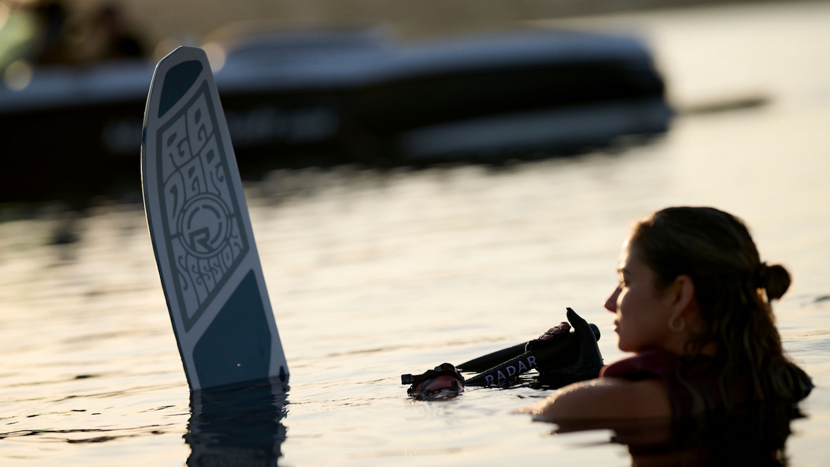 A woman sitting in the water with your Radar Session waterski learning technique on how to get up on a waterski. 