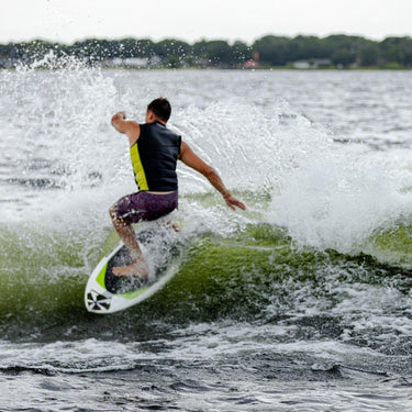 Rider throwing a massive spray with an aggressive slash on the powerful Phase 5 AKU wakesurf board.