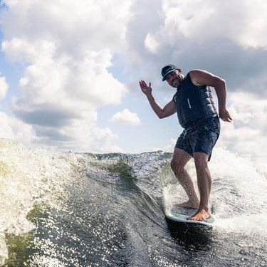 Bigger wakesurfer having fun doing a hang ten and waving to the boat on the stable Phase 5 Cap'tin Wakesurf Board.