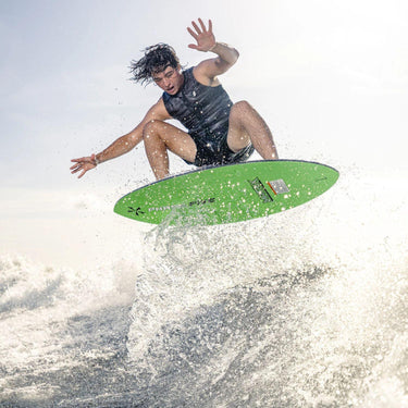 Pro wakesurfer launching a massive ollie 180 air off the lip of the wave on the 2026 Phase 5 Matrix skimmer.