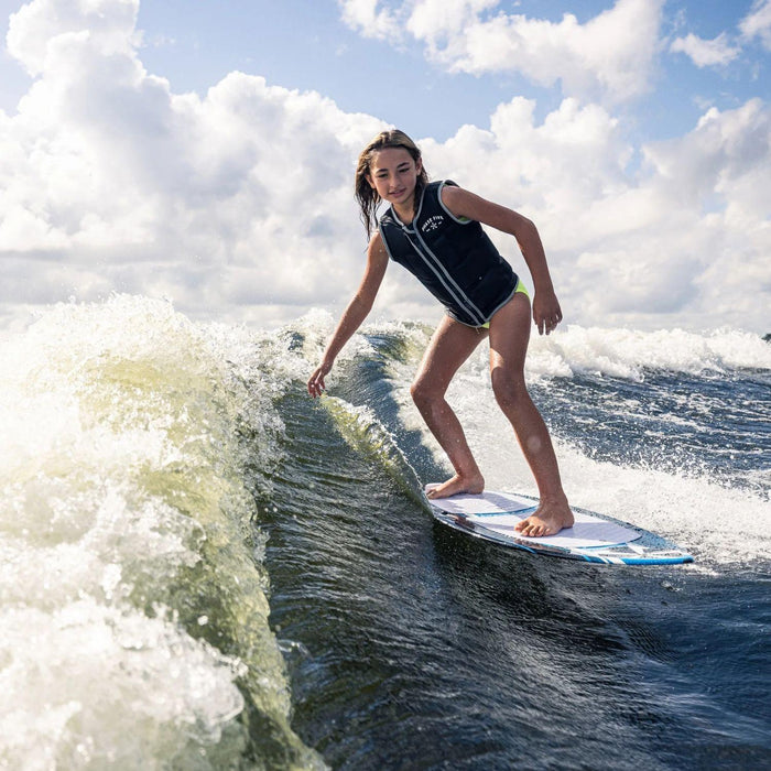Young grom successfully surfing the wave on the stable Phase 5 Scamp kid's board.