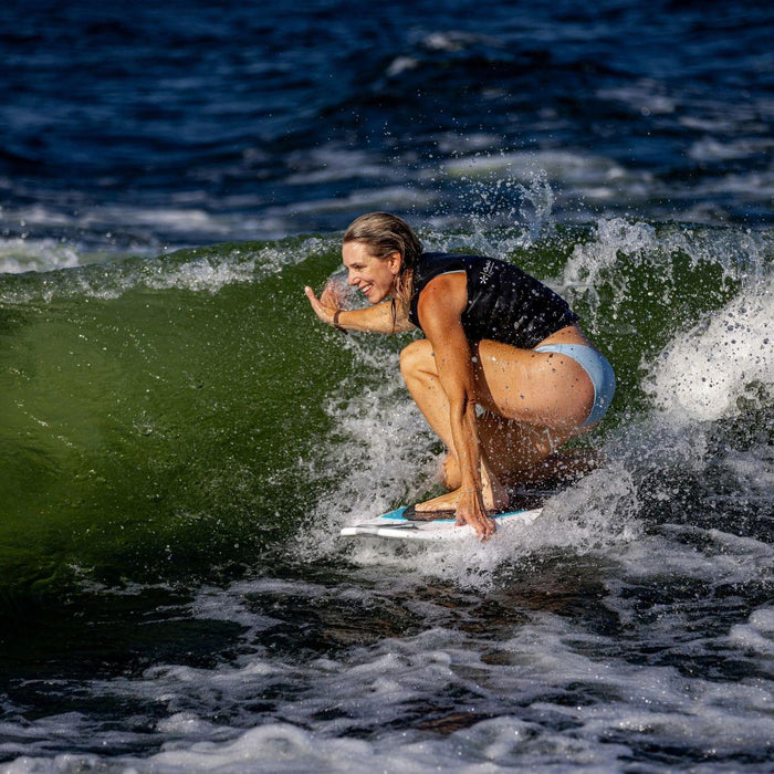 Pro rider Stacia Bank kneeling on her signature Phase 5 Swell Wakesurfer in the sweet spot of the wake.
