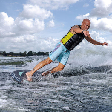 Wakesurfer executing a deep, powerful bottom turn at the base of the wave on the Phase 5 Trident.