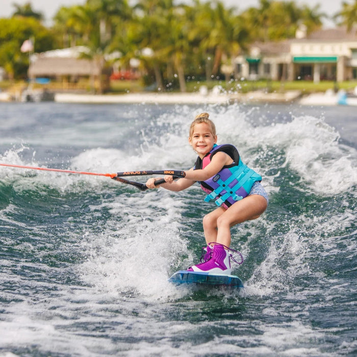 Young girl smiling while wakeboarding on the Ronix August, demonstrating confidence and stability.
