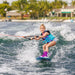 Young girl smiling while wakeboarding on the Ronix August, demonstrating confidence and stability.