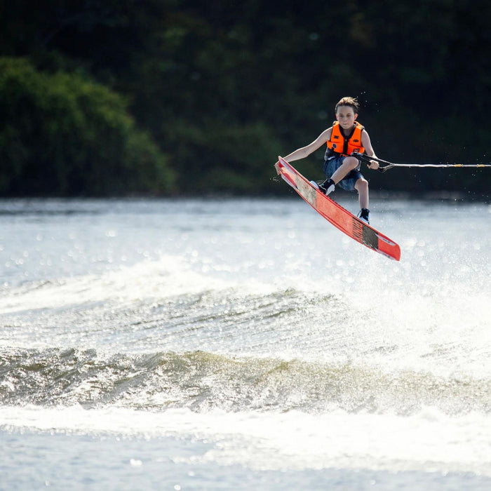 Intermediate youth rider performing a massive wake-to-wake tail grab on the 2026 Ronix District 129cm.