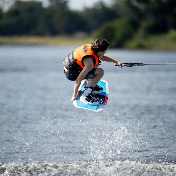 Youth rider executing a technical Tindy grab jump on the versatile Ronix District 129cm wakeboard.