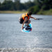 Youth rider executing a technical Tindy grab jump on the versatile Ronix District 129cm wakeboard.