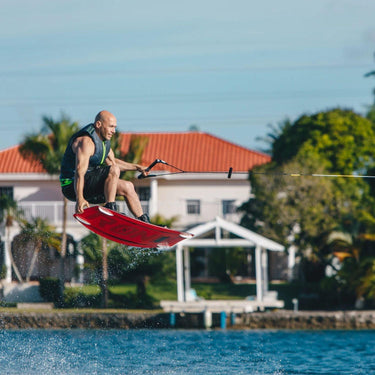 Rider launching a clean tail grab wake-to-wake jump on the complete 2026 Ronix District wakeboard package.