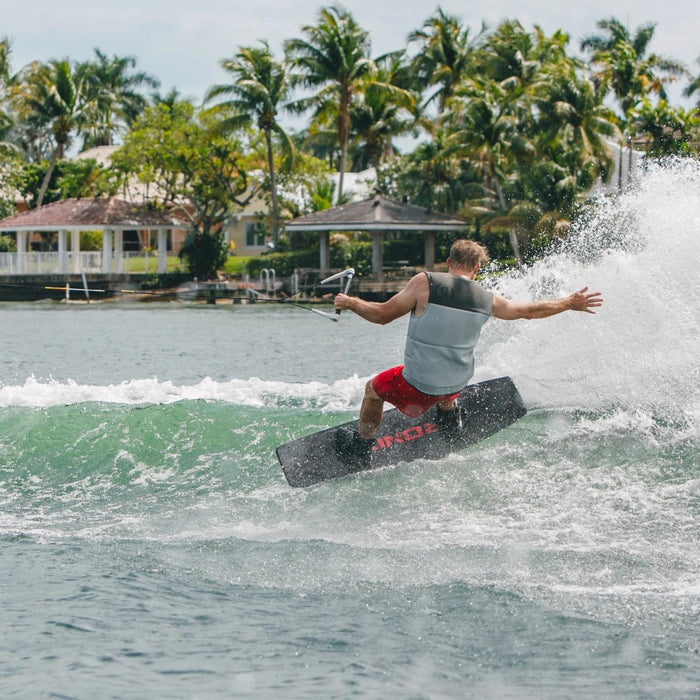 Rider performing a powerful heelside slash on the versatile 2026 Ronix District wakeboard.
