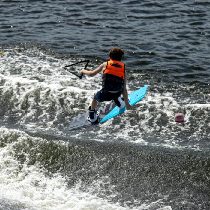 Youth rider executing a Tindy grab wake-to-wake jump on the stable Ronix Kid's Vault.