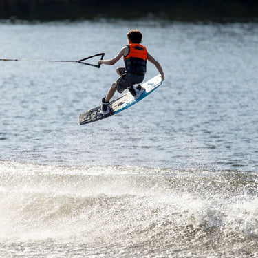 Young grom wakeboarder confidently executing a tailgrab in the air on the complete 2026 Ronix Kid's Vault wakeboard package.