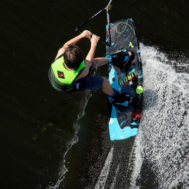 Young grom wakeboarder smiling and learning how to carve outside the wake on the complete 2026 Ronix Vision 120cm wakeboard package.