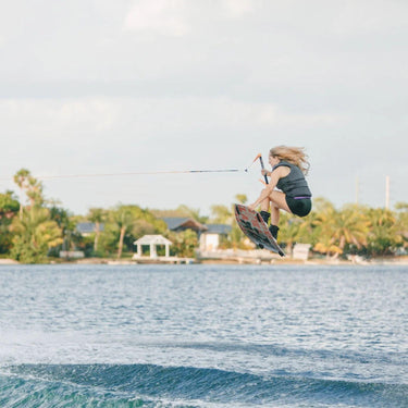 Pro rider Kira Lewis executing a clean wake-to-wake grab on a Ronix Quarter 'til Midnight wakeboard setup.