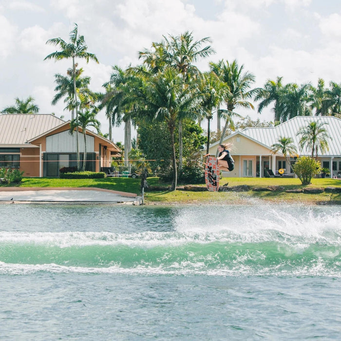 Pro rider Kira Lewis executing a clean wake-to-wake 180 nose grab on the Ronix Quarter 'til Midnight wakeboard.