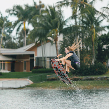 Pro rider Kira Lewis executing a massive wake-to-wake air and locking in a clean nose grab on her Ronix Quarter 'til Midnight wakeboard setup.