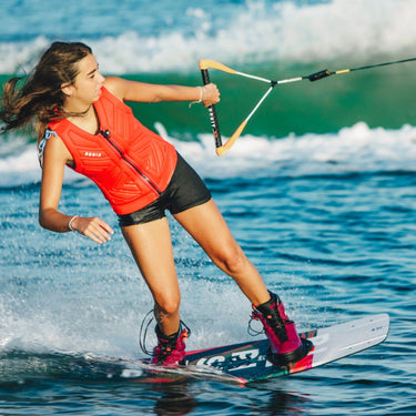 A female wakeboarder carving with precision using the complete 2026 Ronix Rise board and boot setup.