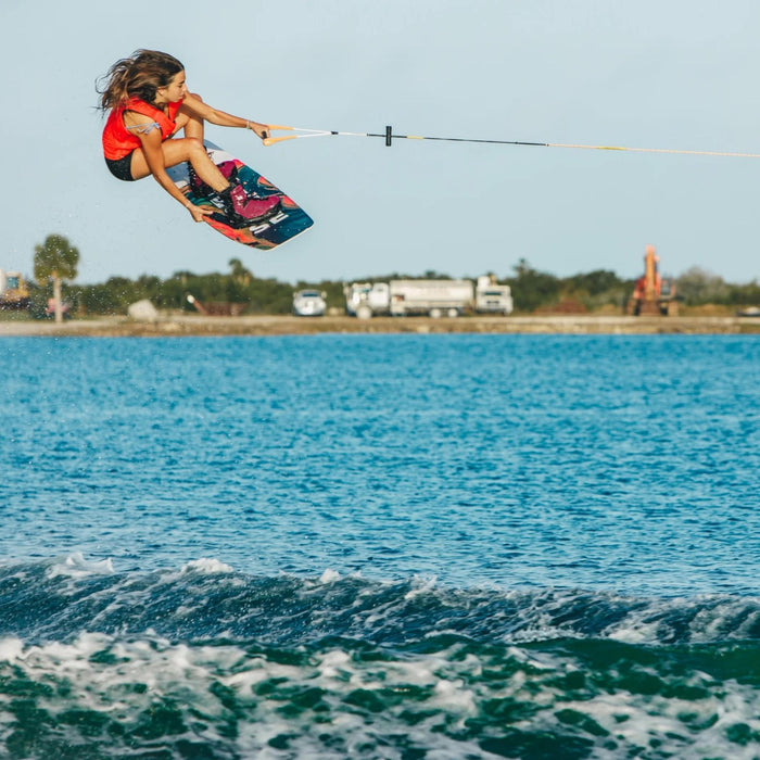 Female pro rider catching massive air with a poked-out tindy grab on the 2026 Ronix Rise.
