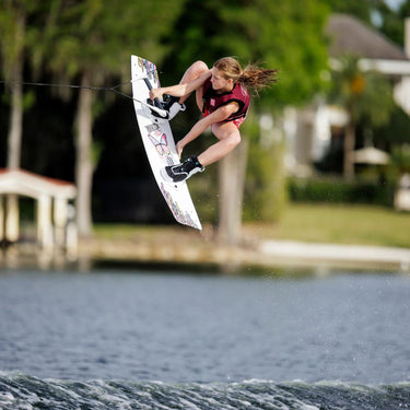 Young female grom executing a clean roast beef grab on the girl's RX1 wakeboard with Ronix Vision Pro boots.