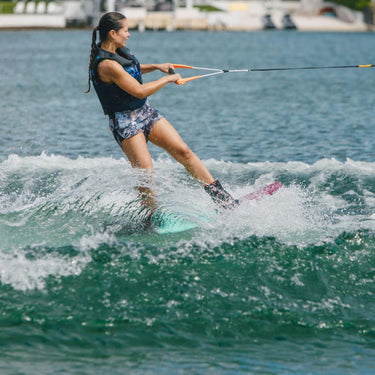 Female wakeboarder confidently cutting into the wake on a heelside edge using the 2026 Ronix Krush wakeboard setup.