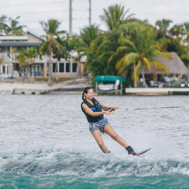 Female wakeboarder building line tension and loading up for a toeside wake jump on the 2026 Ronix Krush wakeboard setup.