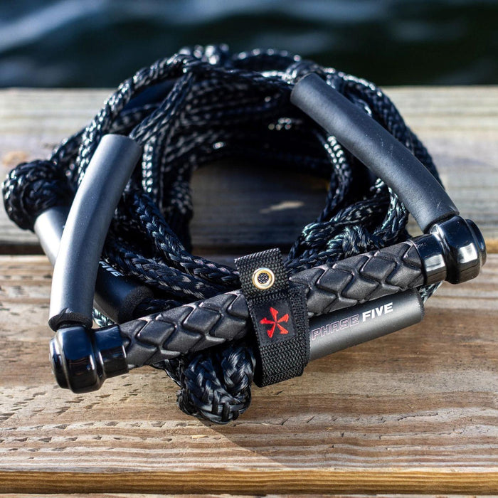 Black Phase 5 Standard Wakesurf Rope resting on a dock - Wakesports Boat Accessories.