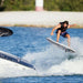 Rider performing a high ollie off the wake on a Ronix Atlantik Flyweight Pro wakesurfer.