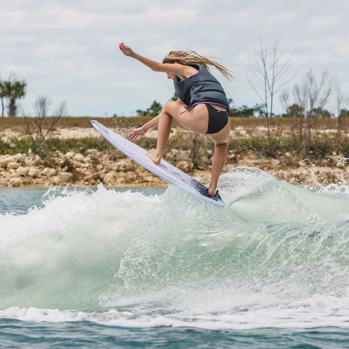 Advanced female rider performing an ollie nose grab air on the 2026 Ronix Aura Flyweight skimmer.