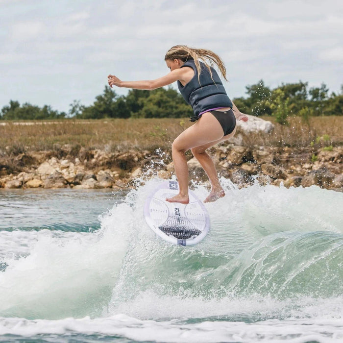 Close-up of a female rider performing a clean air shuv-it on the responsive Ronix Aura skimmer.