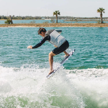 Wakesurfer performing an air 180 on the performance-oriented Ronix Takeoff soft-top board.